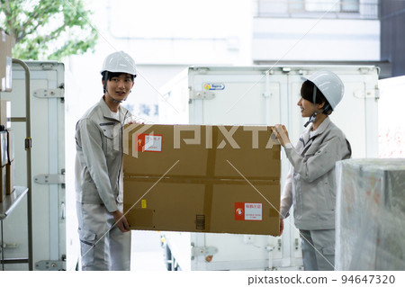 Staff carefully transporting packages in the warehouse 94647320
