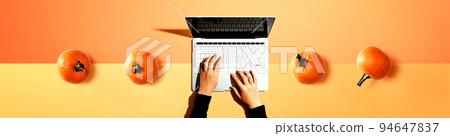 Autumn pumpkins with person using a laptop computer 94647837