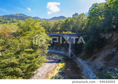 Drone photography | Concrete arch bridge through the forest | No. 5 Otofuke River Bridge on the former Japanese National Railways Shihoro Line | Kamishihoro Town, Hokkaido 94648069