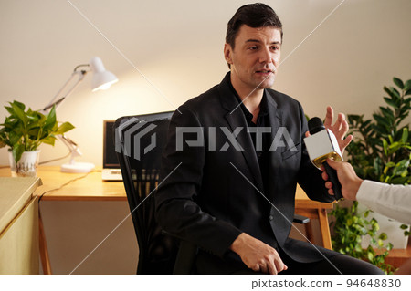 Successful entrepreneur answering questions of TV anchor with microphone Successful entrepreneur answering questions of TV anchor with microphone 94648830