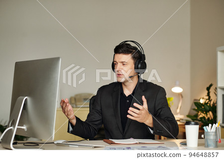 Entrepreneur in headset discussing project details with coworker during online meeting 94648857