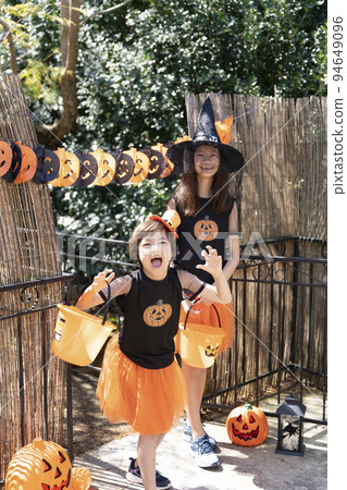 兩個穿著萬聖節服裝的女孩在玩搗蛋或款待 兩個穿著萬聖節服裝的女孩在玩搗蛋或款待 94649096