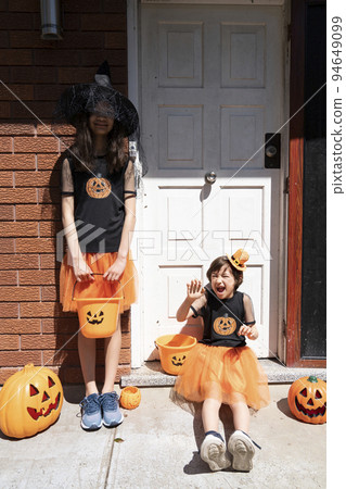兩個女孩在用萬聖節服裝裝飾的房子門前 兩個女孩在用萬聖節服裝裝飾的房子門前 94649099