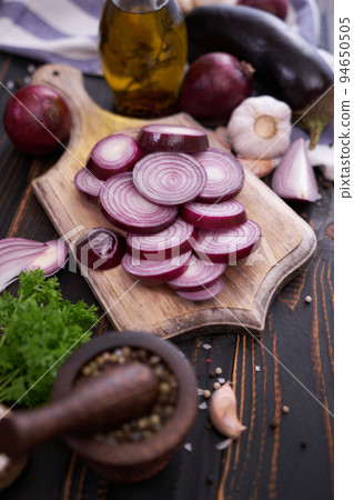 Red Onion on wooden cutting board with dark background Red Onion on wooden cutting board with dark background 94650505