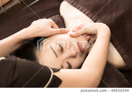 A woman receiving a facial massage 94650594