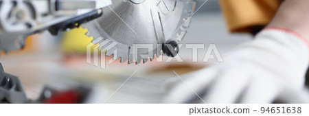 Gloved hands working with a circular saw, close-up Gloved hands working with a circular saw, close-up 94651638