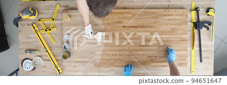 Carpenters apply varnish to a wooden surface, close-up 94651647