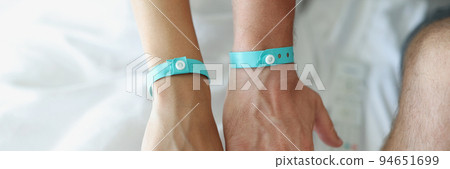 On the male and female hands a blue hotel bracelet 94651699