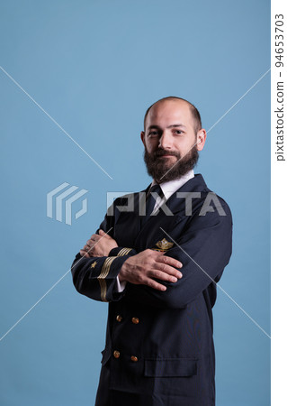 Airplane pilot wearing uniform portrait standing with crossed arms, confident plane captain looking at camera, studio medium shot. Serious civil aviator with badge on professional suit Airplane pilot wearing uniform portrait standing with crossed arms, confident plane captain looking at camera, studio medium shot. Serious civil aviator with badge on professional suit 94653703