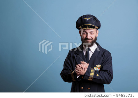 Smiling excited plane aviator in professional uniform clapping hands. Happy positive airlane pilot applauding, shaking palms, standing, looking at camera, studio medium shot Smiling excited plane aviator in professional uniform clapping hands. Happy positive airlane pilot applauding, shaking palms, standing, looking at camera, studio medium shot 94653733