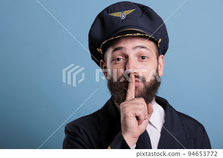 Airplane pilot showing silent gesture, looking at camera with forefinger on lips. Aviation academy plane captain front view, airforce aviator keeping secret, quiet, silence sign 94653772
