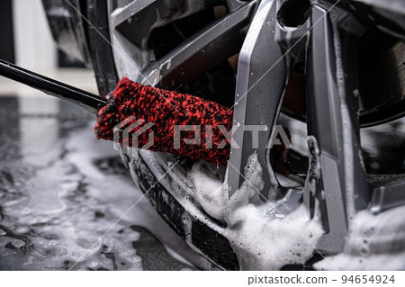 employee of a car wash or a car detailing studio carefully cleans car rims  94654924