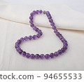Purple stone necklace on white cloth background 94655533