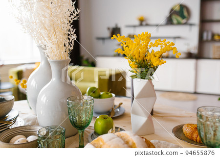 Bright spring mimosa in a ceramic geometric vase in the decor serving a festive or home table in the kitchen 94655876