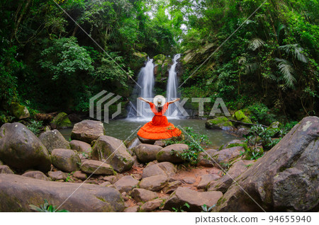 Beautiful woman in red dress in front of the Sapan Waterfall, Khun Nan National Park, Boklua District, Nan Province, Thailand. Beautiful woman in red dress in front of the Sapan Waterfall, Khun Nan National Park, Boklua District, Nan Province, Thailand. 94655940