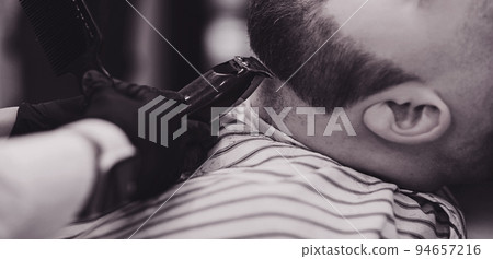 Barber cuts a man's beard Barber cuts a man's beard 94657216