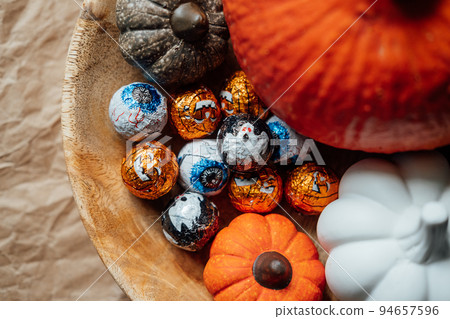 Sustainable and low waste Halloween candy for trick-or-treating. Foil covered eyeballs candies and Halloween decor in wooden plate Sustainable and low waste Halloween candy for trick-or-treating. Foil covered eyeballs candies and Halloween decor in wooden plate 94657596
