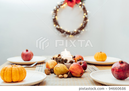 Fall table setting for celebration Thanksgiving day family party. Autumn composition with candles, fruits, nuts and cones. Plates with pumpkins and pomegranate. Natural autumn decor. Selective focus 94660686