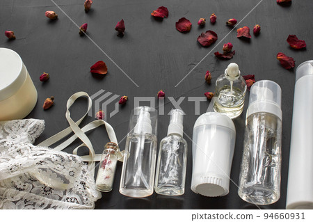 Composition with skin care cosmetic products without label and white lingerie on a black desktop background. 94660931