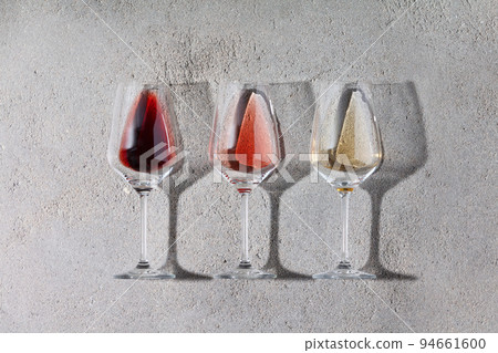 Flat-lay of red, rose and white wine in glasses on grey stone background Flat-lay of red, rose and white wine in glasses on grey stone background 94661600
