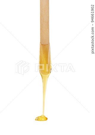 Golden sugar paste or wax for depilation dripping from wooden stick isolated on white background. Golden sugar paste or wax for depilation dripping from wooden stick isolated on white background. 94661902