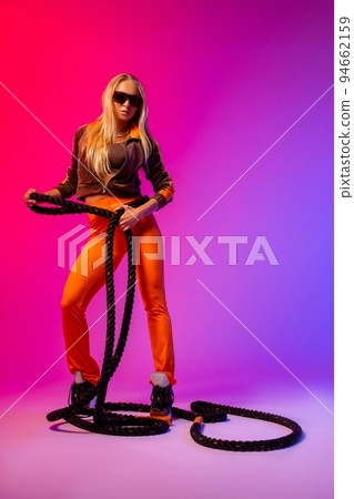 Self assured lady with battle rope standing in bright studio Self assured lady with battle rope standing in bright studio 94662159