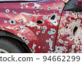 Damaged and destroyed civilian car with shrapnel holes from Russian missile in a war zone in Kharkiv, Ukraine 94662299