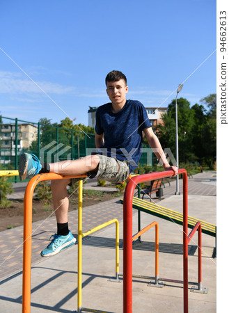 a teenage boy trains on a sports ground outdoors, he does physical exercises, a healthy lifestyle, a bright sunny day in summer 94662613
