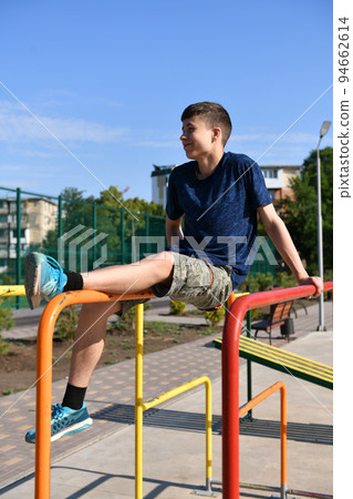 a teenage boy trains on a sports ground outdoors, he does physical exercises, a healthy lifestyle, a bright sunny day in summer 94662614