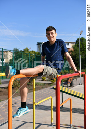 a teenage boy trains on a sports ground outdoors, he does physical exercises, a healthy lifestyle, a bright sunny day in summer 94662615