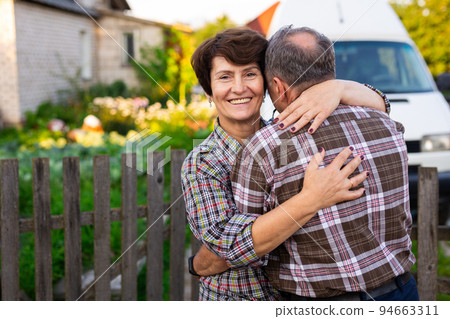 mature happy man and woman hugging at the infield near the fence mature happy man and woman hugging at the infield near the fence 94663311
