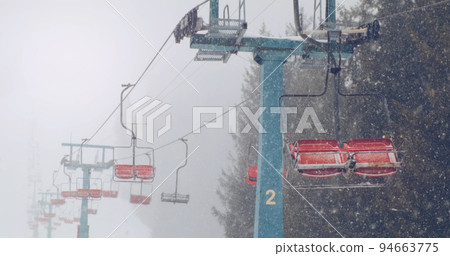 Empty ski lifts in snow winter, backdrop of mountain snowy forest. Ski chairlifts no motion. Stormy weather, snow blizzard in mountains ski resort without people. Nobody. Heavy snowfall 94663775