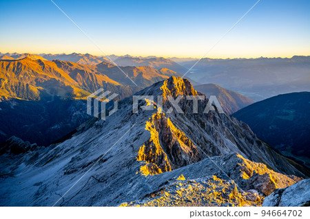 Alpine mountain peaks illuminated by rising sun 94664702