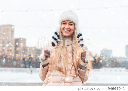Happy winter time in big city charming girl standing street dressed funny fluffy hat. Enjoying snowfall, expressing positivity, smiling to camera 94665041