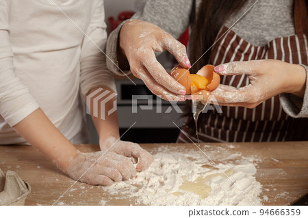 Mother and her daughter are baking a bread and having fun at the kitchen. 94666359