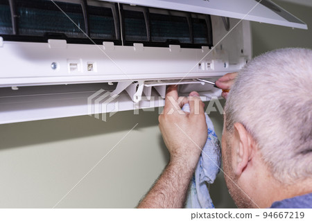 Male technician cleaning air conditioner indoors Male technician cleaning air conditioner indoors 94667219