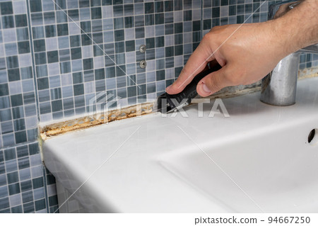the master cleans the mold from the seams of the tiles in the bathroom the master cleans the mold from the seams of the tiles in the bathroom 94667250