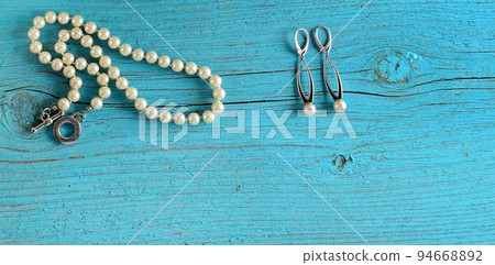 Pearl necklace and earrings on blue background. Wide photo. Free space for text. 94668892