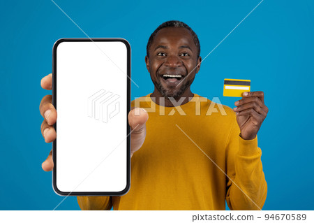 Happy black man holding smartphone and credit card, mockup Happy black man holding smartphone and credit card, mockup 94670589