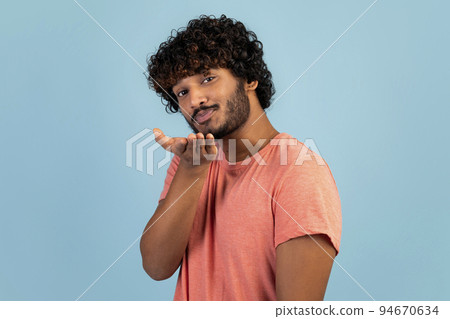 Handsome young indian guy sending fly kiss, blue background 94670634