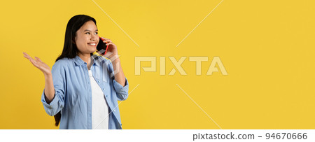 Cheerful confused excited young chinese female student in casual gesturing and calling on smartphone 94670666