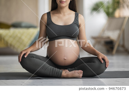 Pregnant Young Woman In Activewear Sitting On Yoga Mat At Home, Cropped Pregnant Young Woman In Activewear Sitting On Yoga Mat At Home, Cropped 94670873