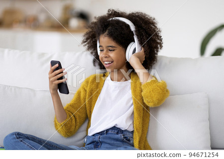 Happy african american preteen girl listening to music Happy african american preteen girl listening to music 94671254