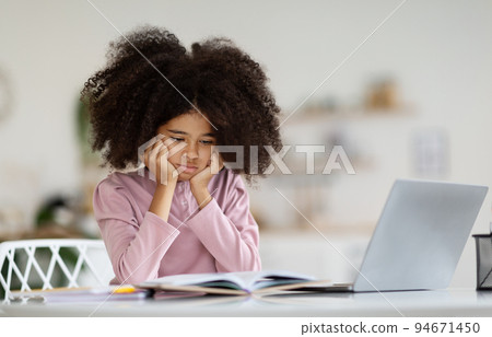 Bored black kid schooler suffering while doing homework Bored black kid schooler suffering while doing homework 94671450