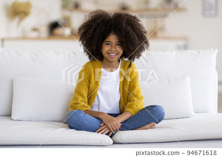 Cheerful african american girl sitting on couch at home 94671618