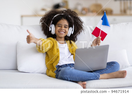 Happy african american girl using laptop, showing French flag 94671914