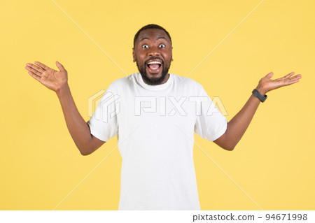 Cheerful African American Guy Shrugging Shoulders Over Yellow Studio Background Cheerful African American Guy Shrugging Shoulders Over Yellow Studio Background 94671998