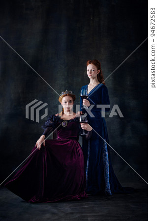 Portrait of two beautiful women in image of royal persons, queen and princess, isolated over dark background Portrait of two beautiful women in image of royal persons, queen and princess, isolated over dark background 94672583