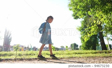 schoolgirl goes to school through the park along the path. concept of children. people in the park. schoolgirl goes to school in education park. schoolgirl walks after class with a backpack dream schoolgirl goes to school through the park along the path. concept of children. people in the park. schoolgirl goes to school in education park. schoolgirl walks after class with a backpack dream 94673230
