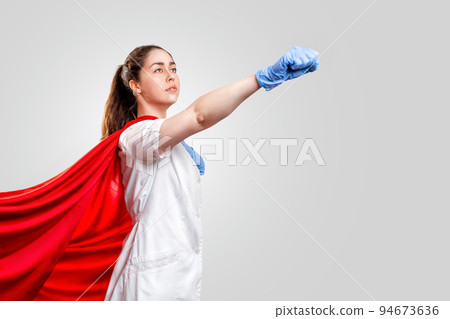 A doctor or nurse in medical gloves and a red superhero Cape on a gray background, rushes to help. The concept of a super hero power for clinics and hospitals. Copy space A doctor or nurse in medical gloves and a red superhero Cape on a gray background, rushes to help. The concept of a super hero power for clinics and hospitals. Copy space 94673636